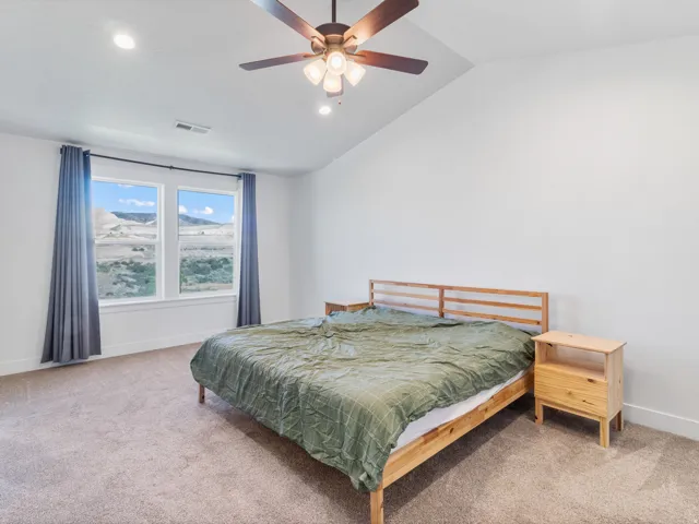 Spacious room featuring a vaulted ceiling with a ceiling fan, recessed lighting, and expansive windows offering distant mountain scenery