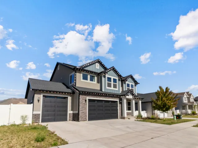 Contemporary two-story residence featuring a stone and siding facade, a two-car garage, a single-car garage, multiple windows, and a paved driveway
