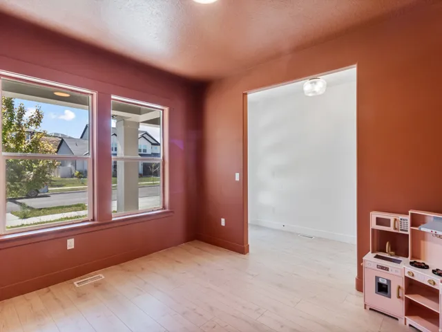 Interior room featuring light wood-finish flooring, two large windows, and a doorway opening to an additional space