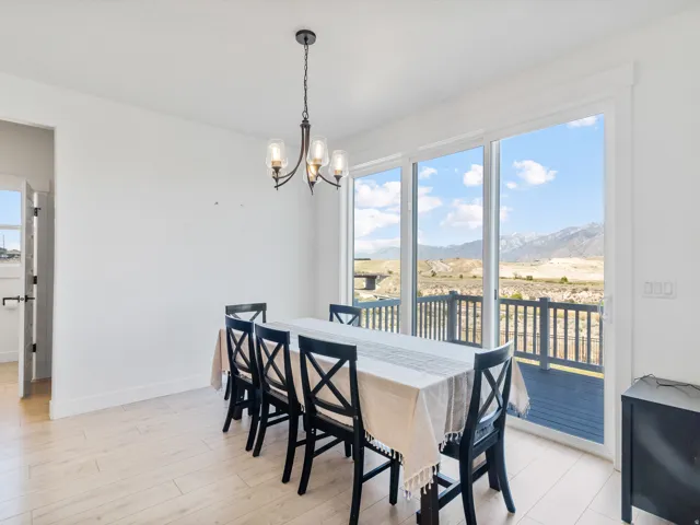 Bright dining area featuring wood-finish flooring, a contemporary chandelier, and large sliding glass doors opening to an outdoor deck