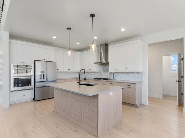 Modern kitchen with light wood-finish flooring, white upper cabinetry, and contrasting light wood-finish lower cabinetry
