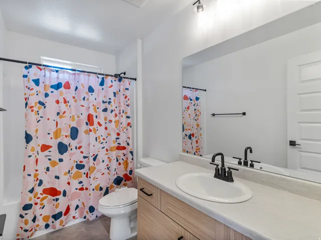Bathroom featuring a single vanity with wood-finish cabinetry, a white oval sink, and a black faucet