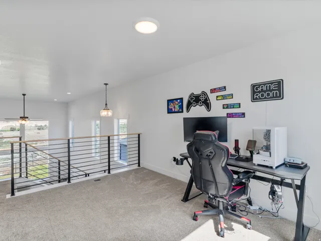 Carpeted loft area featuring a contemporary horizontal metal railing with a wood-finish top rail, recessed lighting, and a pendant light fixture