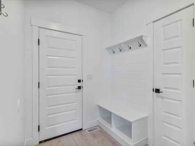 Entryway featuring a built-in bench with open storage, shiplap accent wall, and a shelf with black hooks