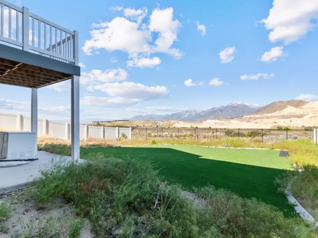 Expansive backyard featuring a dedicated artificial turf area, concrete patio, and mountain backdrop