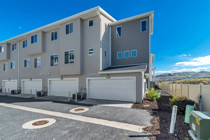 Modern townhome exterior featuring a light gray stucco finish and contrasting horizontal siding