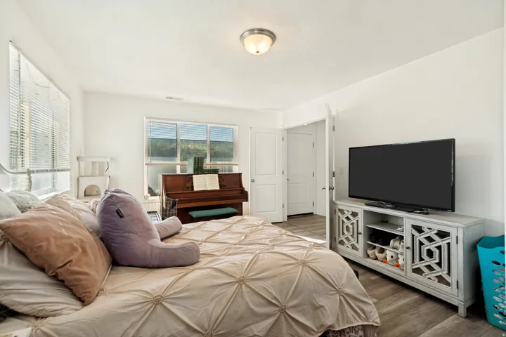Spacious room featuring light-colored walls, wood-finish flooring, and multiple windows with blinds