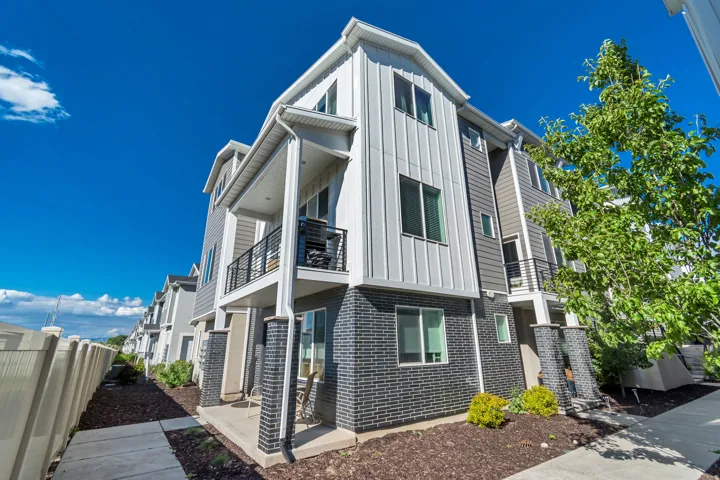 Modern multi-story facade featuring dark brick accents, vertical white siding, and horizontal gray siding