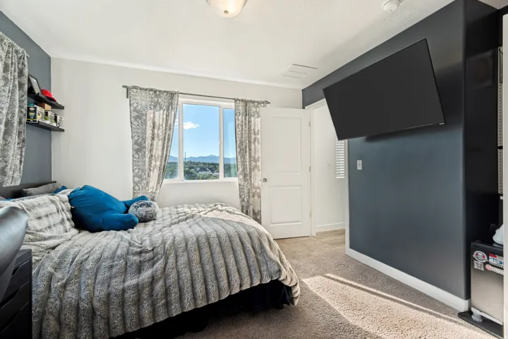 Bright room featuring a window with a mountain backdrop, wall-mounted television, and built-in shelving