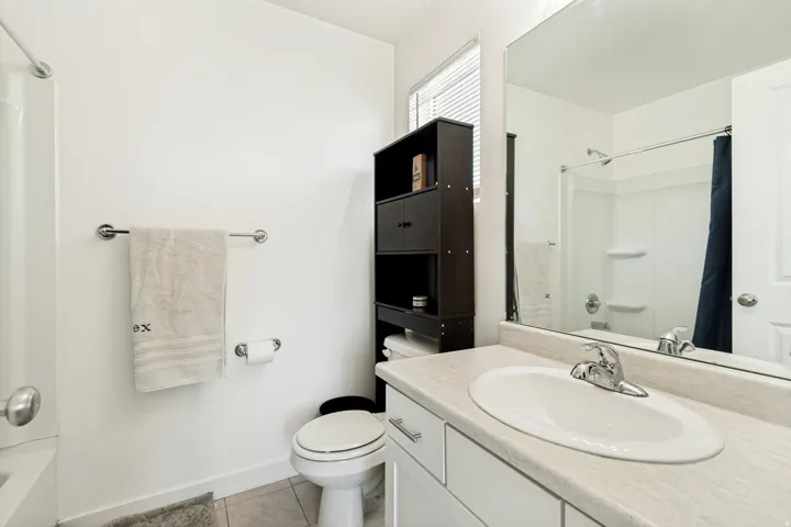 Bathroom featuring a white vanity with an integrated sink, chrome fixtures, and a large wall-mounted mirror