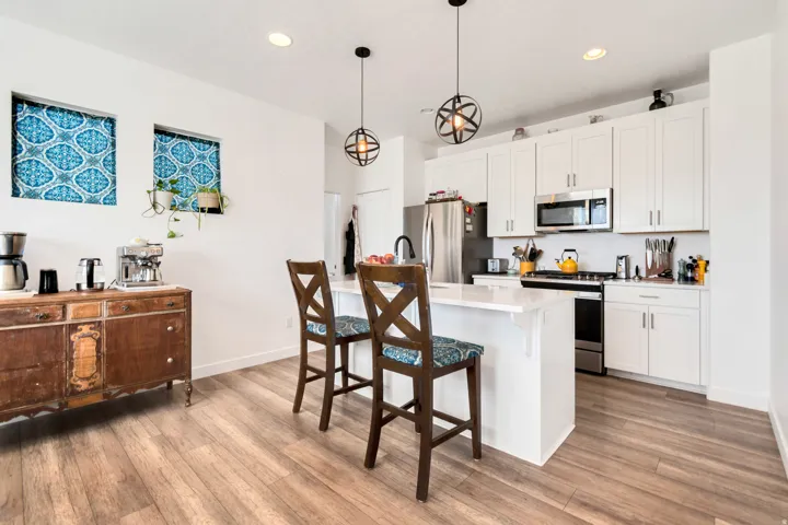 Modern kitchen featuring white cabinetry, stainless steel appliances, a center island with seating, and wood-finish flooring