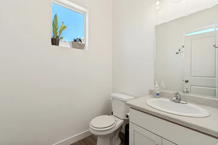 Bathroom vanity with a white integrated sink, gray countertop, and an expansive wall-mounted mirror