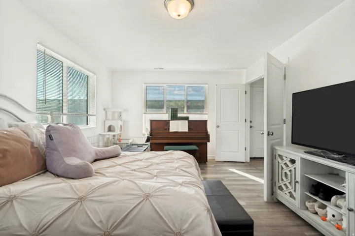 Bright room featuring two windows, light wood-finish flooring, white walls, and a recessed ceiling light fixture