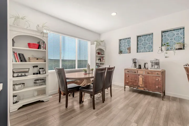 Open-concept dining area featuring light wood-finish flooring, a large window with horizontal blinds, and recessed lighting