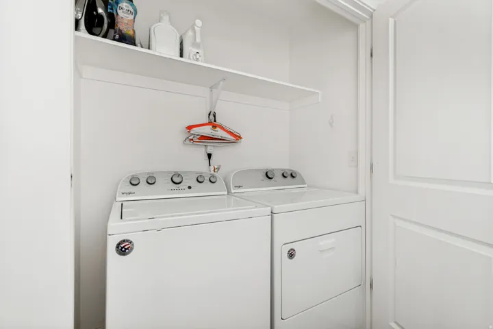 Dedicated laundry area featuring a white washer and dryer, an overhead shelf for storage, and a wall-mounted drying rack