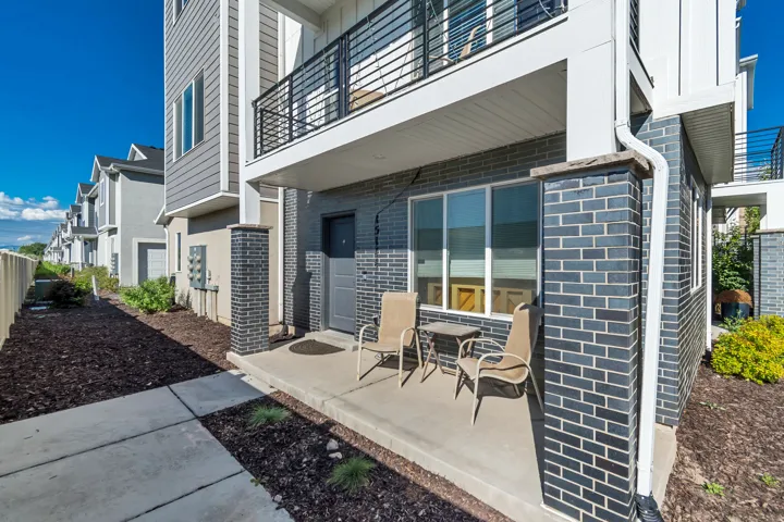 Patio featuring concrete flooring, blue-gray brick accents, and a window with white trim