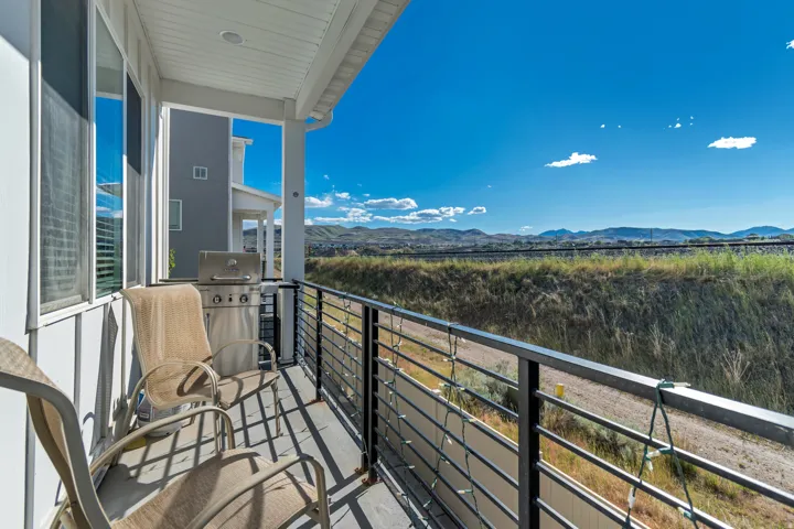 Covered balcony featuring a horizontal slat railing, wood-finish flooring, and a corrugated metal accent wall