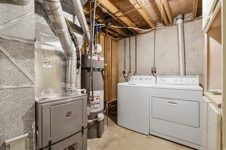 Dedicated utility space featuring a washing machine, dryer, water heater, and furnace