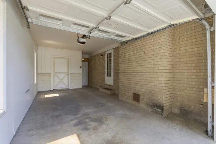 Attached garage featuring a light brick wall, concrete flooring, and a paneled overhead door
