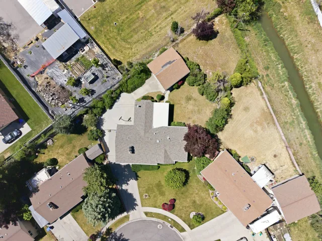 Single-story residence with a brown shingle roof, mature landscaping, and an attached garage