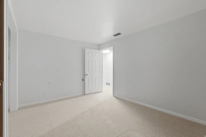 Bright interior room featuring neutral-toned carpet flooring, white baseboards, and light gray wall paint