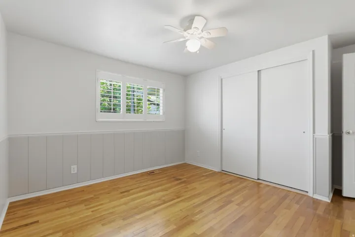 Interior room featuring wood-finish flooring, white paneled wainscoting, and white wall paint