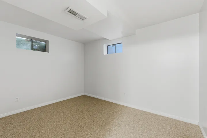 Bright room featuring plush carpet flooring, white painted walls, white trim, and two elevated windows