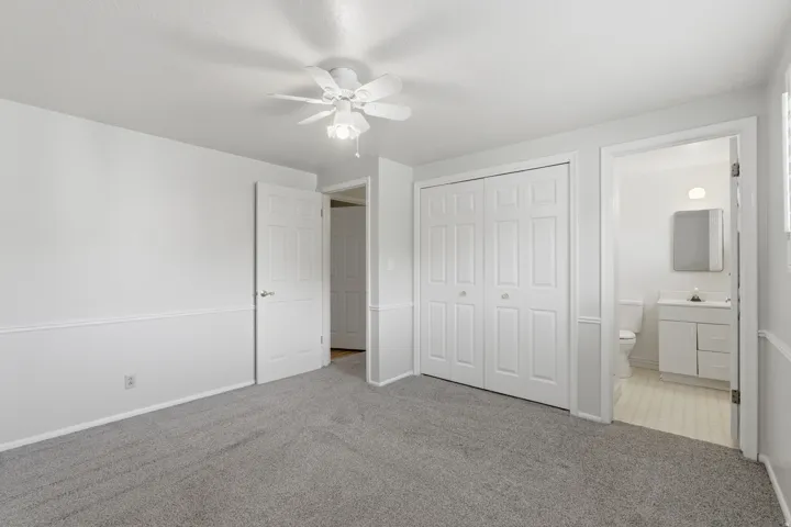 Carpeted room with a ceiling fan, crown molding, and wainscoting