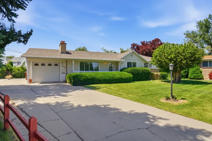 Ranch-style residence featuring a prominent front lawn, mature landscaping, and a concrete driveway