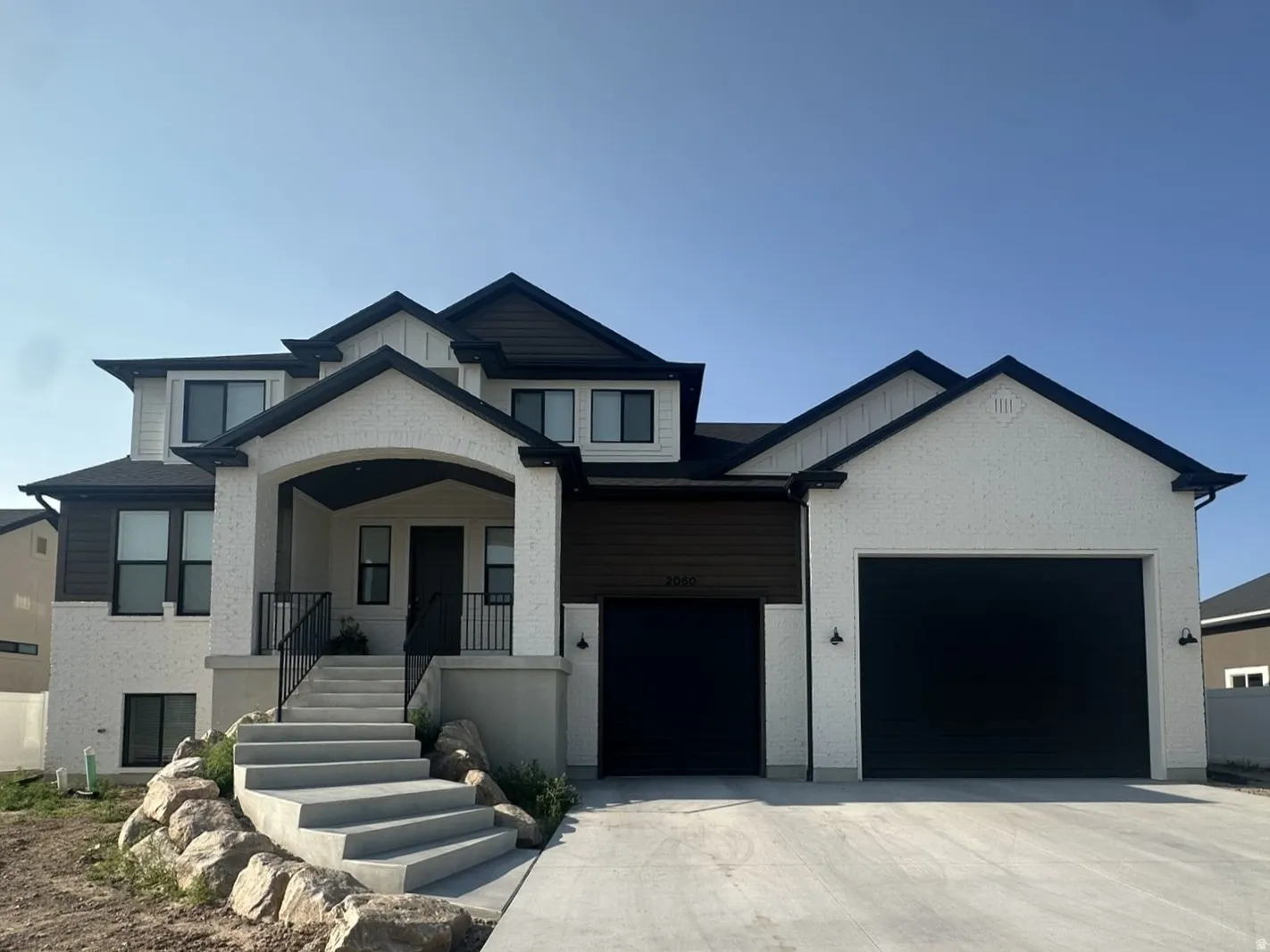 Contemporary three-story residence with a white brick, wood siding and black trim.