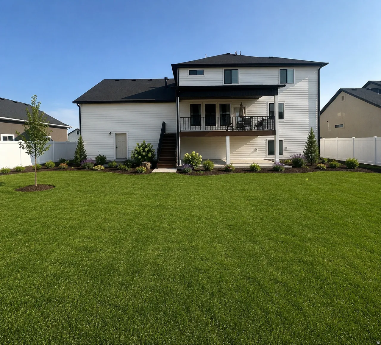 *Unfinished yard. Landscaping generated with AI for visual purposes only.*  Rear exterior featuring a second-story deck with black metal railings, a ground-level concrete patio, and a partially fenced yard.
