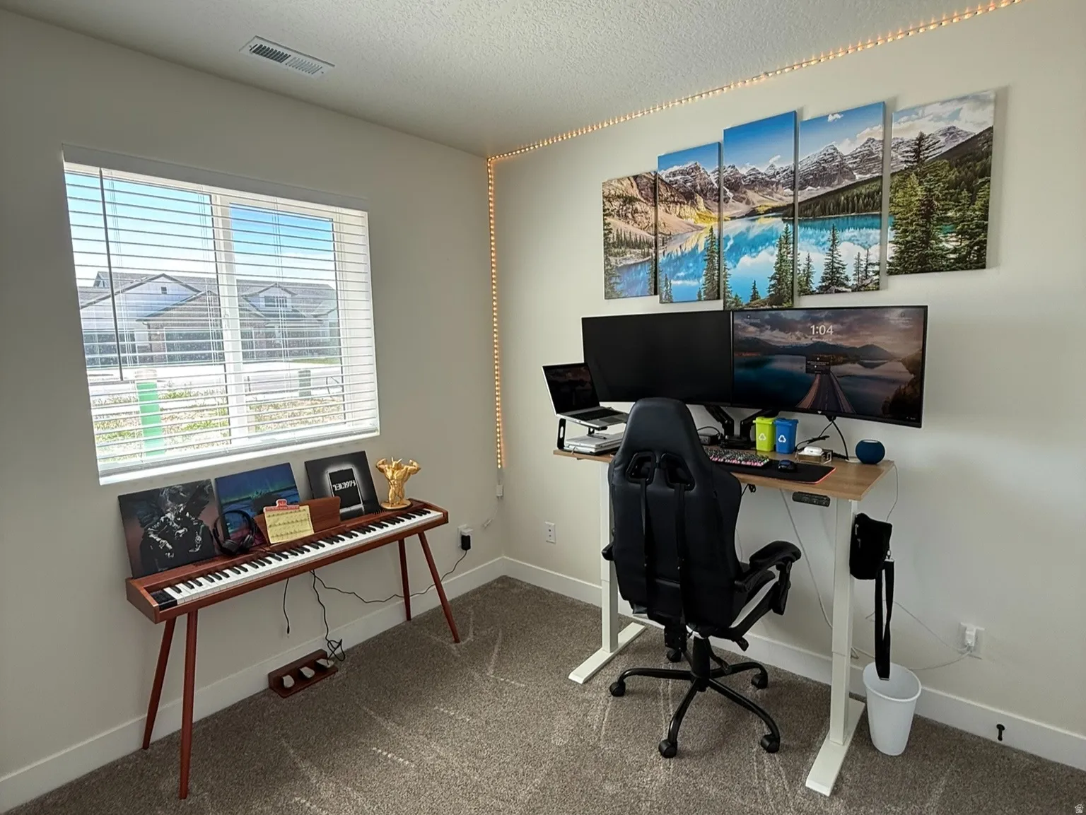 Bright interior space featuring a window with horizontal blinds, neutral wall paint, and a textured ceiling