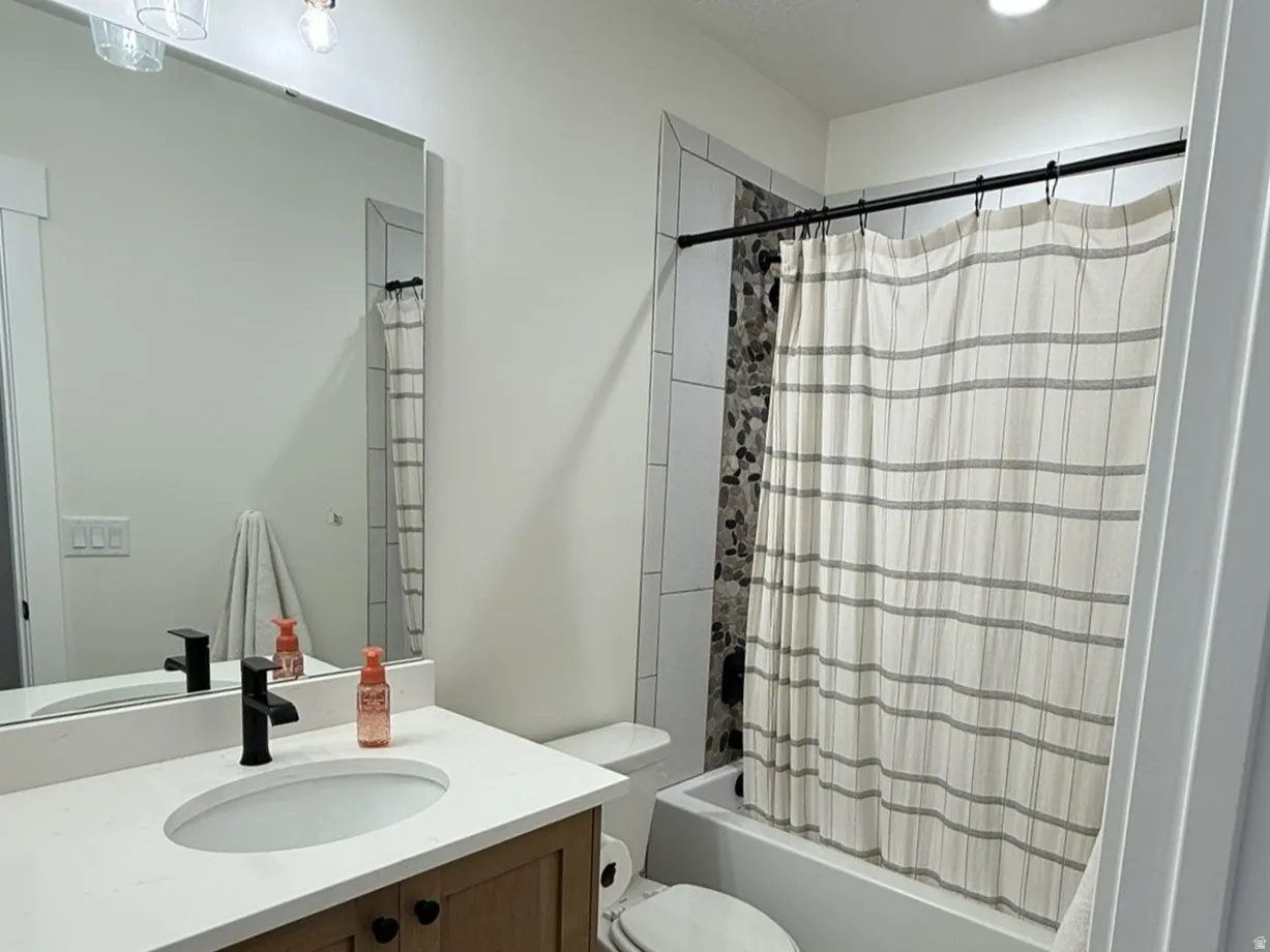 Bathroom featuring a wood-finish vanity with a white countertop, an undermount sink, and a black faucet