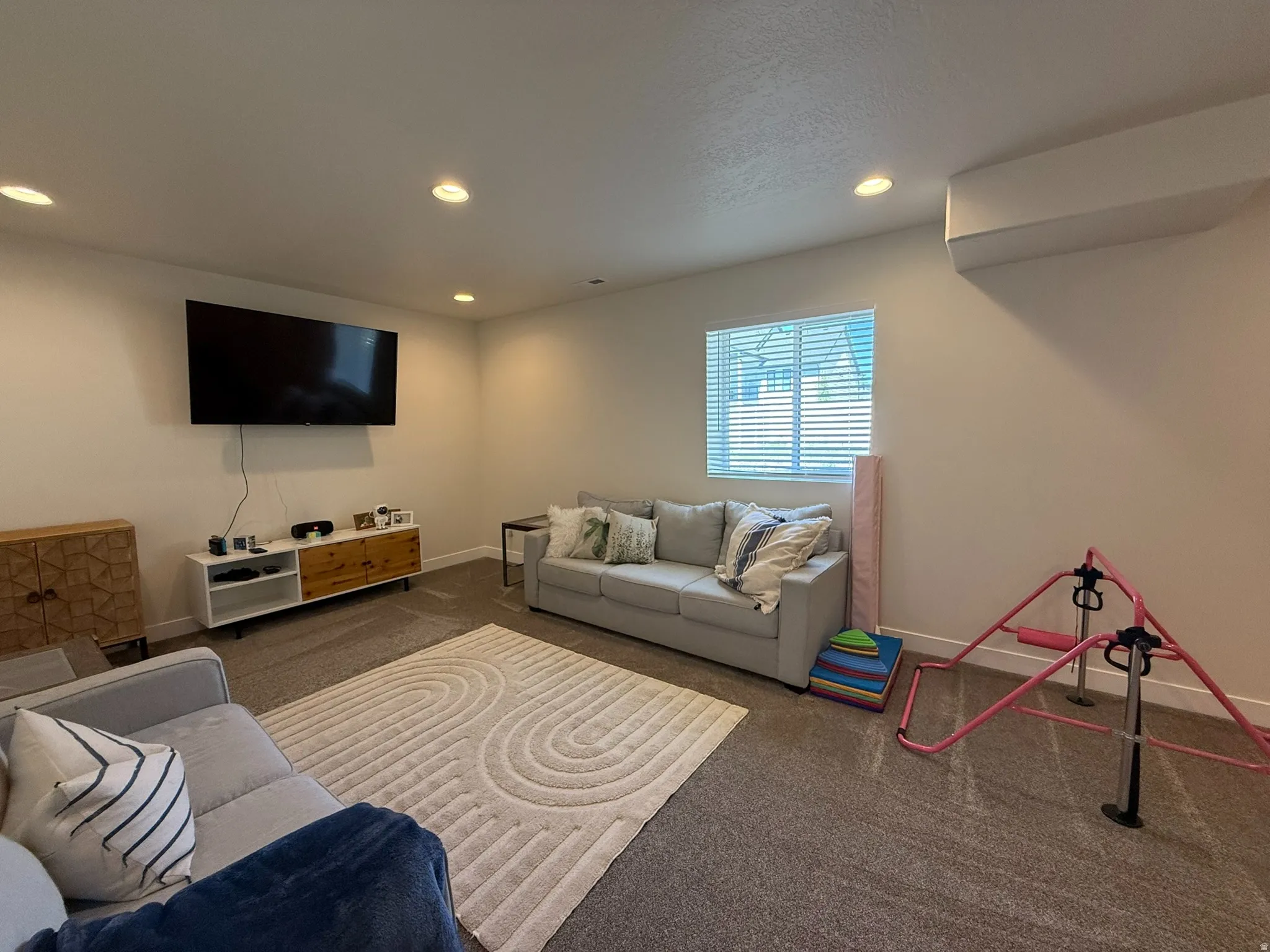Recessed ceiling lighting illuminates this room featuring wall-to-wall carpeting and a daylight window