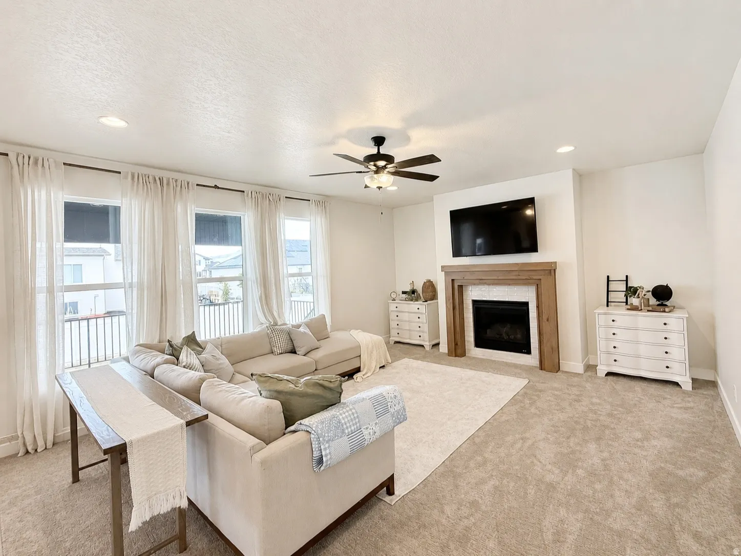 Spacious living area featuring a fireplace with a wood mantle and tile surround, recessed lighting, and multiple windows