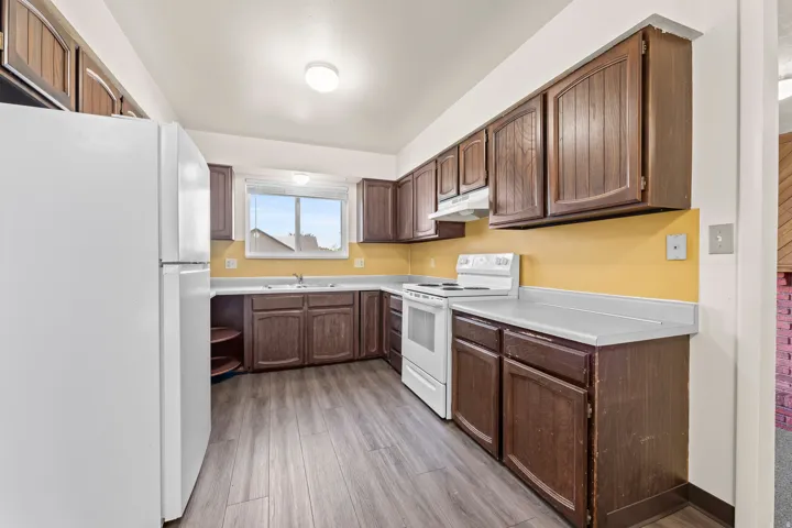 Kitchen featuring wood-finish cabinetry, white countertops, and wood-finish flooring