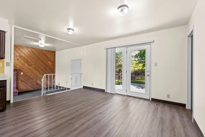 Open-concept living area featuring wood-finish flooring, white walls, and dual glass-paned doors providing exterior access