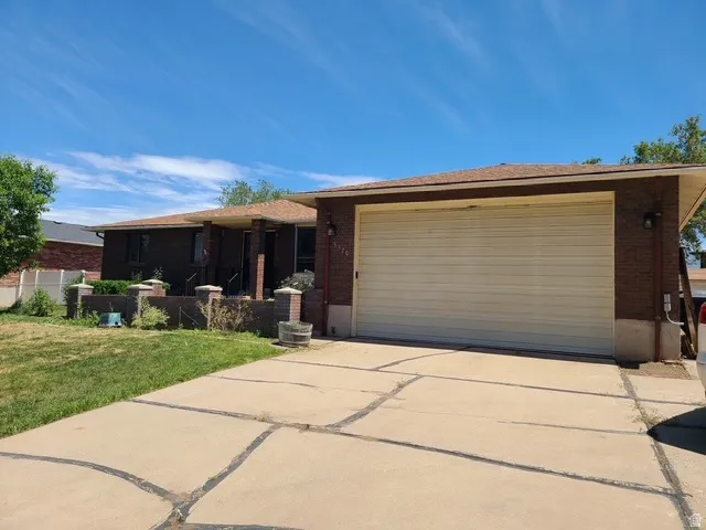 Brick exterior residence with a two-car garage, concrete driveway, and front landscaping elements