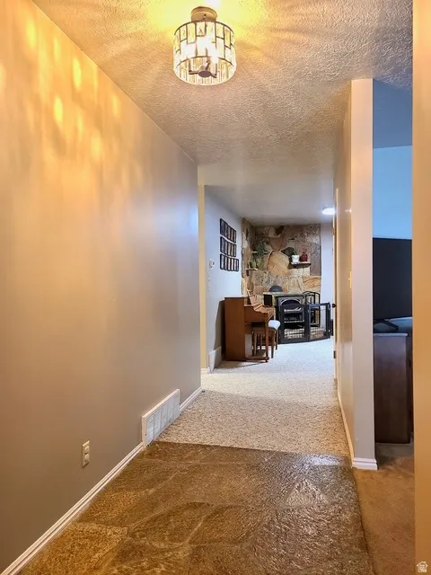 Entryway with textured flooring transitioning to carpet, featuring a decorative overhead light fixture