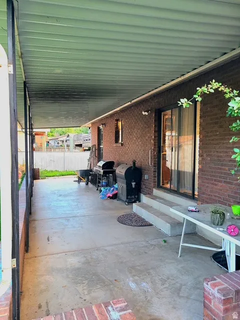 Expansive covered patio featuring a concrete floor, brick exterior wall, and direct access through a sliding glass door