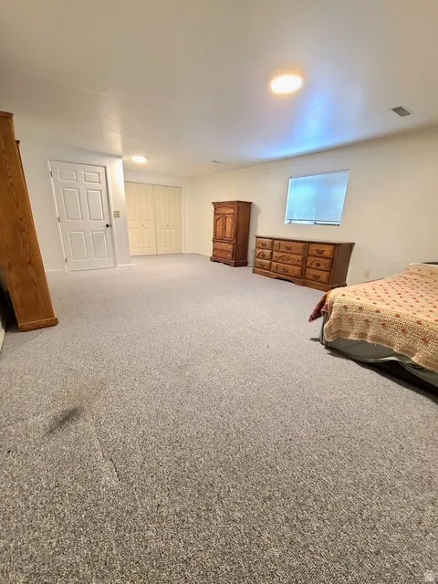 Spacious room with light-colored carpeting and white painted walls