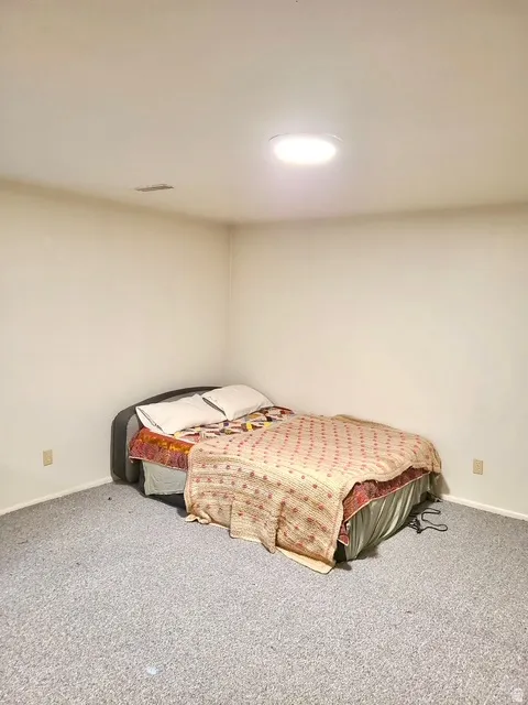 Recessed ceiling light fixture illuminating a carpeted room with neutral-toned walls