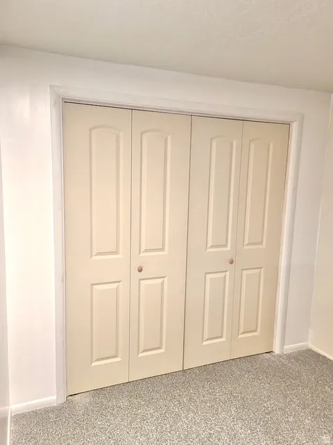 Cream-colored bi-fold closet doors with panel detailing and light-toned knobs