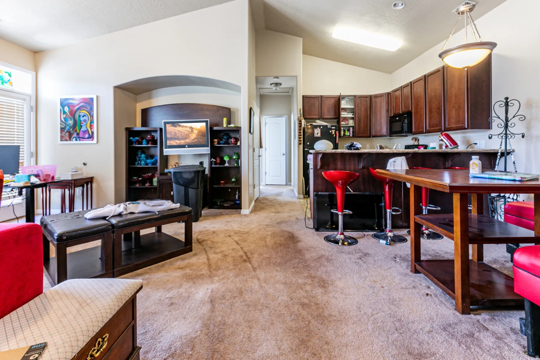Open-concept living space featuring a breakfast bar, dark wood-finish cabinetry, built-in shelving, and vaulted ceilings
