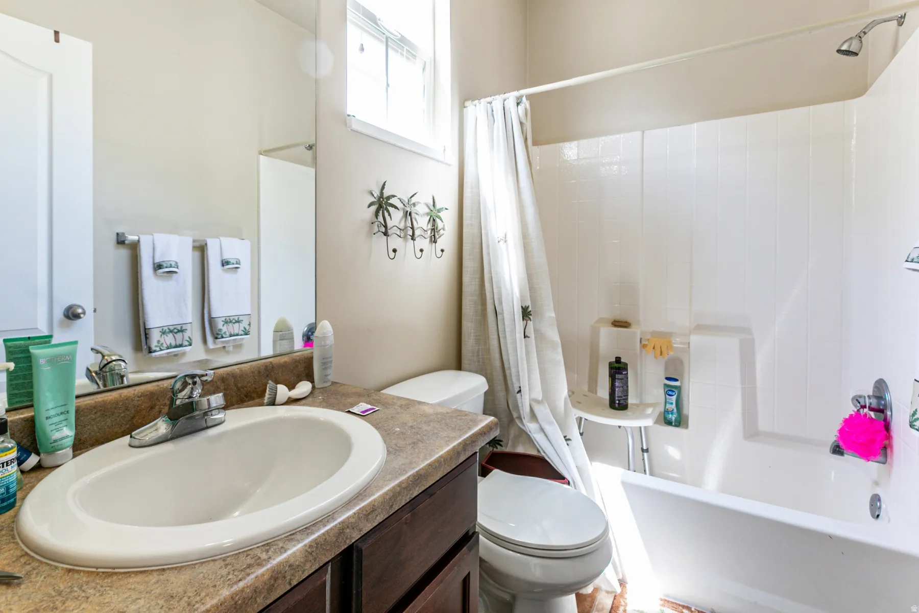 Bathroom featuring an integrated sink with a chrome faucet, dark wood-finish vanity, and a shower-tub combination with a white surround