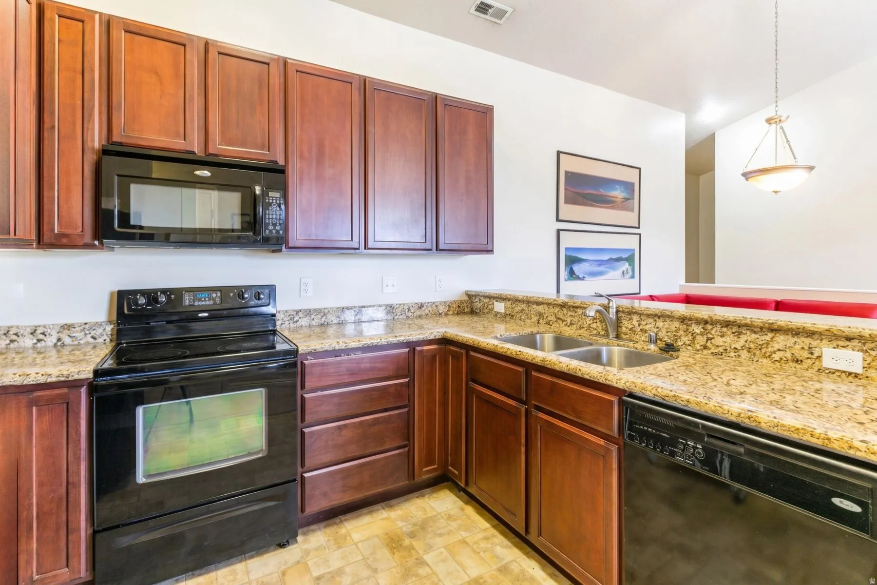 Kitchen featuring wood cabinetry, granite-style countertops, dual basin stainless steel sink, black electric range, and a built-in microwave