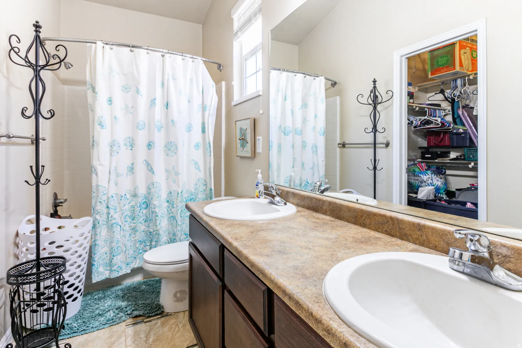 Bathroom featuring a double vanity with integrated sinks, a built-in mirror, an enclosed shower with a shower curtain, and a window providing natural light