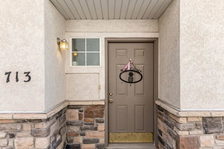 Entryway featuring textured stucco siding and a stone veneer foundation