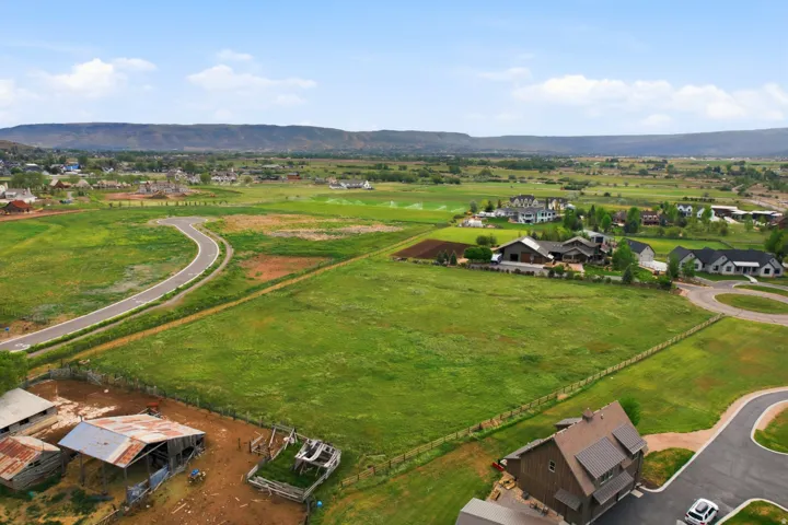 Expansive green fields with distant mountains and established residential structures