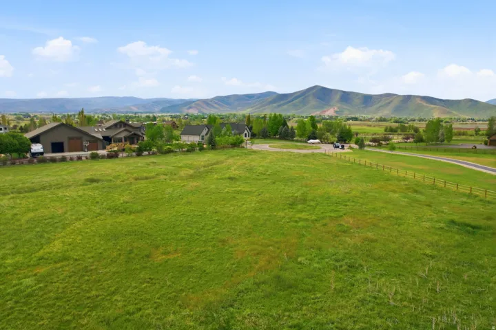 Expansive green pasture with a split-rail fence and a winding road